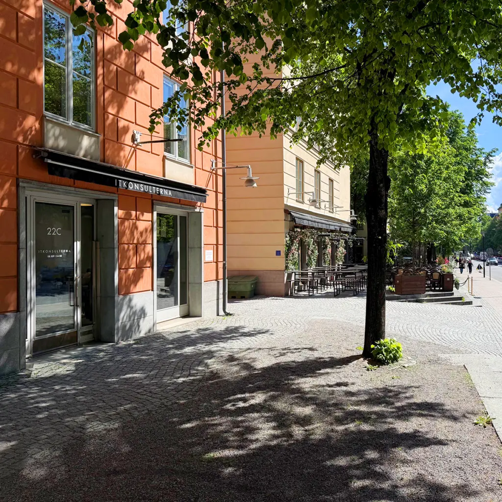 Exteriör av Kungsholmens IT:s kontor vid en trädkantad gata med tegelbyggnad och entré.